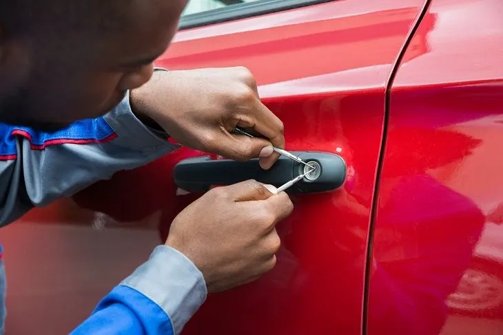Mobile locksmith performing auto lockout services on a sedan in a Tuscaloosa AL parking lot